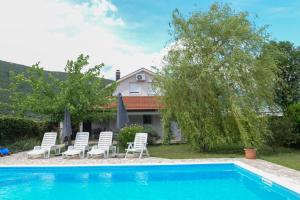una piscina con sillas blancas y una casa en Holiday Home Vemini en Mostar