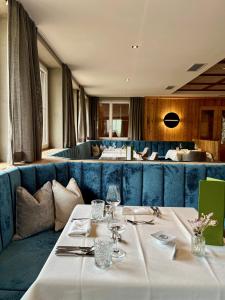 een eetkamer met 2 tafels en een blauwe bank bij Vitalpina Hotel Magdalenahof in Santa Maddalena in Casies