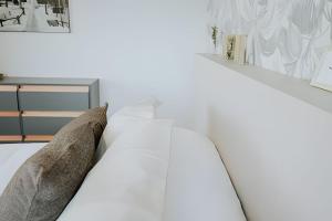 um quarto com uma cama branca com almofadas em Nona Kate em Ushuaia