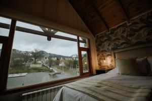 a bedroom with a bed and a large window at Aunaisin - Nona Kate in Ushuaia