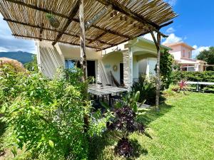 un patio con un banco bajo una pérgola de madera en Jolie maison Borgo trois chambres trois salles de bain en Borgo