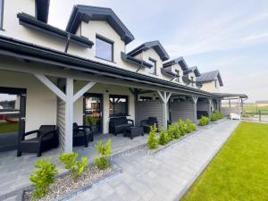 a house with a patio with chairs and plants at Apartamenty SOLEIL in Sarbinowo