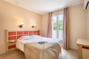 una camera d'albergo con letto e finestra di Résidence Pierre & Vacances L’Anse De Pramousquier a Le Lavandou