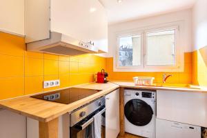 een keuken met gele muren en een wasmachine en droger bij GuestReady - Charming living near Paris in Aubervilliers