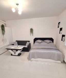 a white bedroom with a bed and a table at Apartament Domi in Gniezno