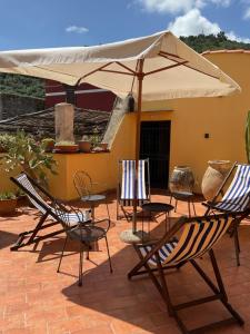 a group of chairs and an umbrella on a patio at Bed & Breakfast Scià Dina in Toirano