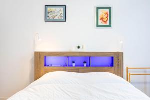 Schlafzimmer mit einem weißen Bett und blauen Lichtern in der Unterkunft GuestReady - Contemporary comfort near Paris in Clichy