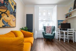 uma sala de estar com um sofá amarelo e uma secretária em GuestReady - Fantastic Apt near Regent's Park em Londres