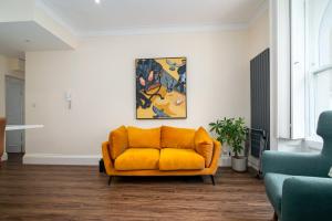 um sofá laranja numa sala de estar com um quadro em GuestReady - Fantastic Apt near Regent's Park em Londres
