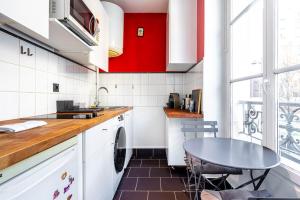 eine Küche mit roten Schränken und einem Tisch in der Unterkunft GuestReady - Modern stay near the Pantheon in Paris