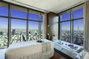 um quarto com uma cama grande, uma banheira e janelas em Mandarin Oriental, Tokyo em Tóquio