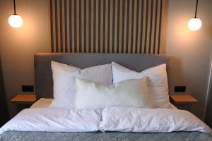 a bed with white pillows on top of it at Penthouse Apartment mit Meerblick und Dachterrasse in Gaski bei Mielno in Gąski +25 photos