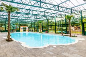 a large swimming pool in a glass building with palm trees at Vakantiepark Vlinderloo in Enschede
