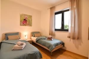 two twin beds in a room with a window at Luxury apartment Porto with sea view and swimming pool in Premantura