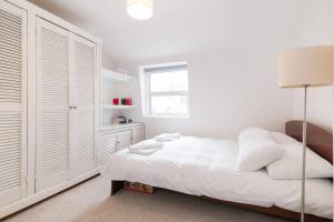 a white bedroom with a bed and a window at GuestReady - Cityscape Retreat near The Shard in London