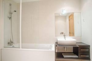 bagno con vasca, lavandino e specchio di GuestReady - Spacious and Modern Studio in Belém! a Lisbona
