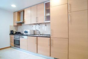 a kitchen with wooden cabinets and a microwave at GuestReady - Spacious and Modern Studio in Belém! in Lisbon