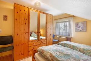 Ferienwohnung Triska في Balve: غرفة نوم بسريرين وخزانة خشبية كبيرة