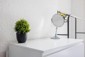 a mirror and a potted plant on a white shelf at Bright & Sunny 2BR Near Westcliff Beach & High St by Everhome Ltd in Southend-on-Sea