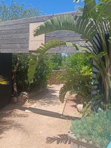 a wooden archway with a sign in a garden at H&ocirc;tel Les Suites Du Maquis in Bonifacio
