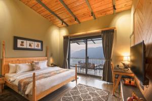 a bedroom with a bed and a balcony at SaffronStays Aruunoday - 4BR with Theatre, Deck & Bonfire in Bhīm Tāl