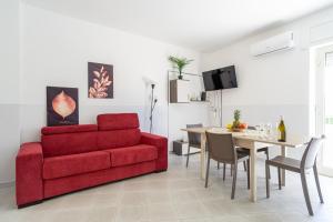 a living room with a red couch and a table at spazioso bicamere fronte mare in Marina di Strongoli +3 photos