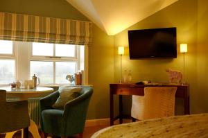 ein Wohnzimmer mit einem TV, einem Tisch und Stühlen in der Unterkunft The Devonshire Fell Hotel in Burnsall