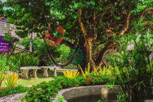 Ocas do Índio Hotel Spa في بيبيريبي: حديقة فيها كرسي وشجر وزهور