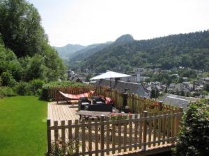 une terrasse avec une table, des chaises et un parasol dans l'établissement Les Camélias, à Le Mont-Dore