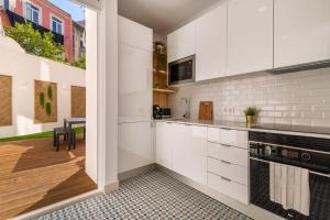 een keuken met witte kasten en een tafel en stoelen bij GuestReady - Dazzling Apt with Private Terrace in Lissabon