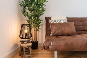 een bruine bank in een woonkamer met 2 planten bij GuestReady - Dazzling Apt with Private Terrace in Lissabon