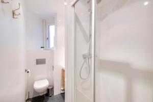 een witte badkamer met een douche en een toilet bij GuestReady - Modern flat near Place De La Bastille in Parijs