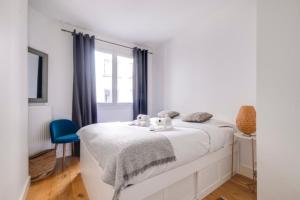een witte slaapkamer met een bed en een blauwe stoel bij GuestReady - Modern flat near Place De La Bastille in Parijs