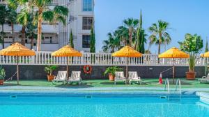 una piscina con sedie e ombrelloni e un hotel di THE BEST OCEAN VIEW a Playa de las Americas