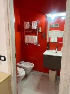 a red bathroom with a toilet and a sink at Hotel Veronese in Genova