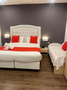 a bedroom with two beds with red pillows at Hotel Veronese in Genova