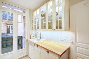 a kitchen with white cabinets and a sink and a window at GuestReady - Bright Flat at Porte d'Auteuil Metro in Paris