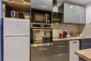 a kitchen with stainless steel appliances and a white refrigerator at GuestReady-Charming Studio 15 mins to Grand Palais in Paris