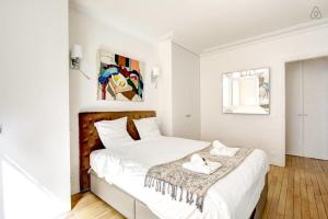 a white bedroom with a large bed with white sheets at GuestReady - Bright Flat at Porte d'Auteuil Metro in Paris