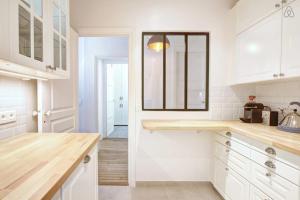 a white kitchen with white cabinets and a window at GuestReady - Bright Flat at Porte d'Auteuil Metro in Paris