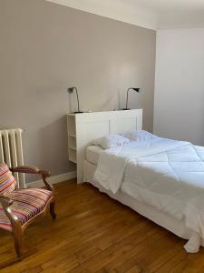 um quarto com uma cama branca e uma cadeira em GuestReady - Amazing 2BR Flat near Passy Village em Paris