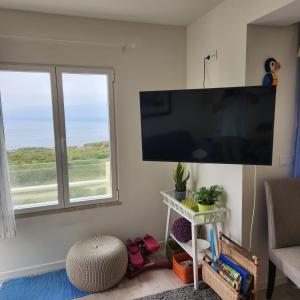 sala de estar con TV de pantalla plana grande en la pared en Ericeira penthouse with total sea view, en Ericeira