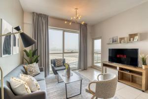 uma sala de estar com um sofá azul e uma televisão em GuestReady - Sunny Delights em Dubai