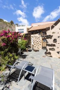 een patio met 2 stoelen en een tafel en een gebouw bij Home2Book Stunning Rustic House El Pinar & WiFi in El Pinar del Hierro