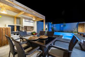 a patio with a table and chairs and a pool at Mr & Mrs Grey Villas-Private Pool Luxury in Zakynthos near Laganas in Ambelókipoi