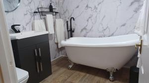 a bathroom with a white bath tub and a sink at The Renishaw Rooms in Renishaw