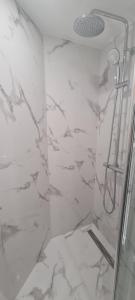 a shower in a bathroom with white marble walls at Geographotel Paris-Roissy CDG Airport in Le Mesnil-Amelot