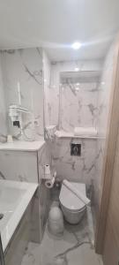 a white bathroom with a toilet and a sink at Geographotel Paris-Roissy CDG Airport in Le Mesnil-Amelot