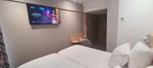 a hotel room with a tv on the wall at Geographotel Paris-Roissy CDG Airport in Le Mesnil-Amelot +23 photos