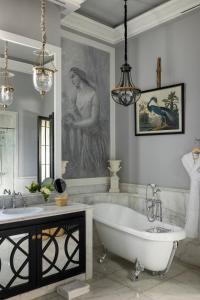 - une salle de bains avec une baignoire et un portrait d'une femme dans l'établissement Palais Ronsard Relais & Chateaux, à Marrakech